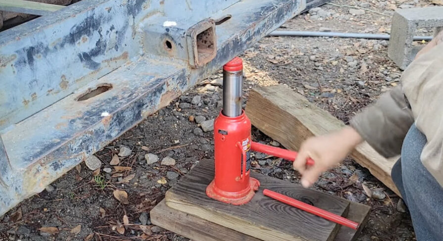 Mechanic lifting the truck with 10-ton bottle jack.