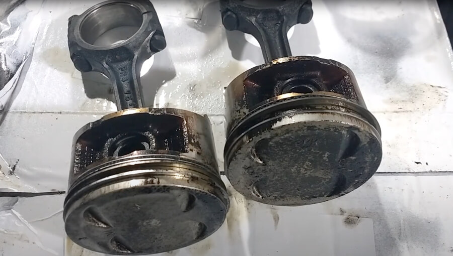 Carbon deposit buildup on pistons and piston rings.