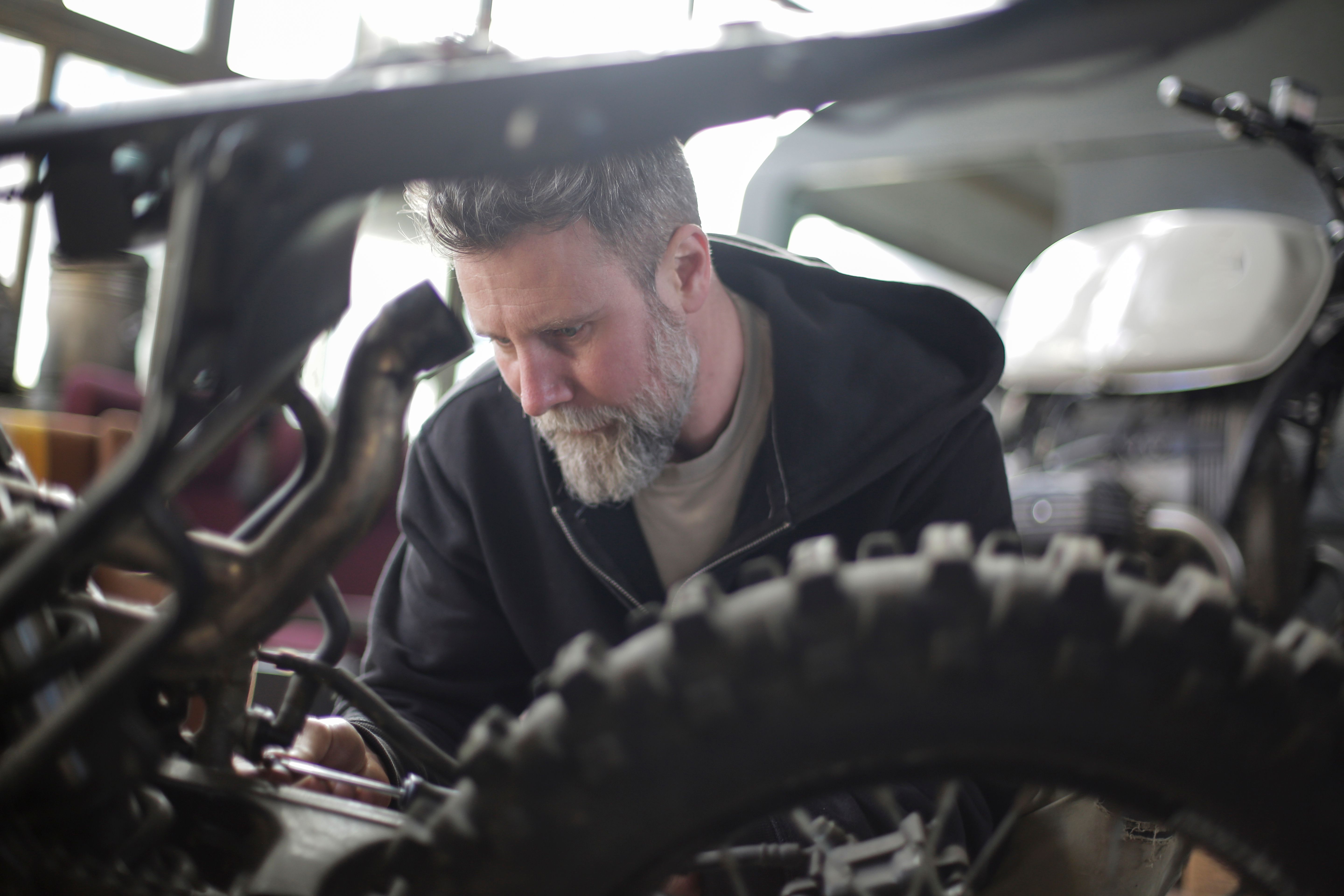 Mechanic inspecting a motorcycle wheel with tools in a garage during pre-trip maintenance