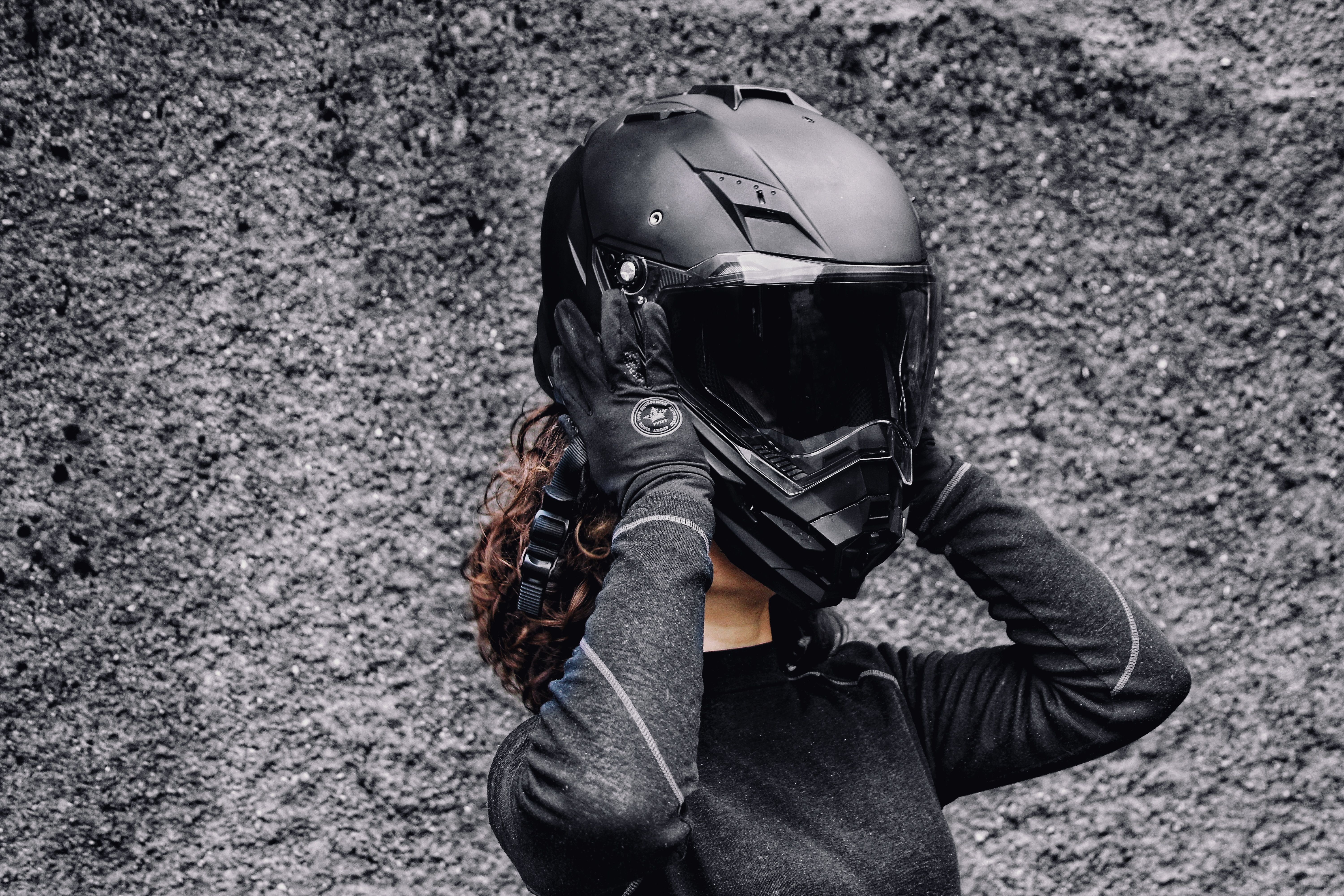 Woman putting on a motorcycle helmet and gloves as protective riding gear before a long trip